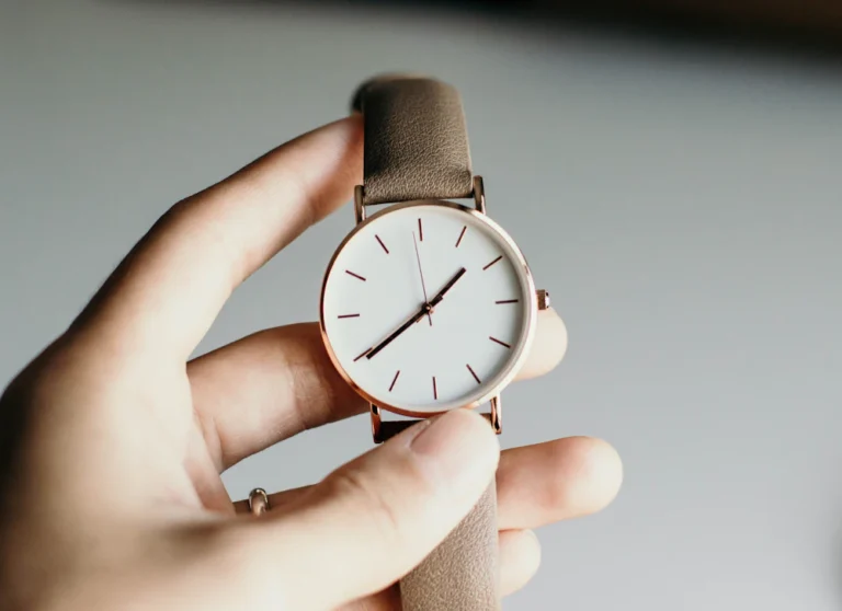 Analog watch with white dial held in hand