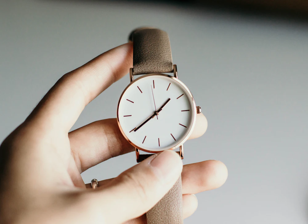 Analog watch with white dial held in hand